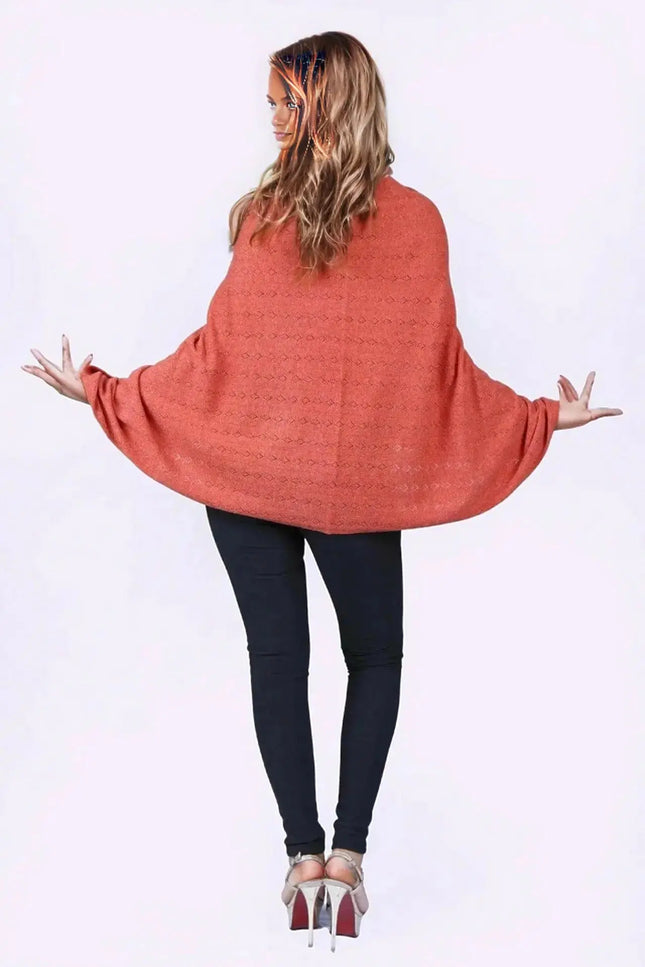 KCI 120 cashmere poncho with woman in red sweater and black pants standing with arms out