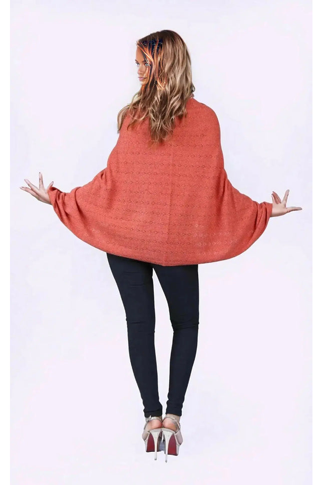 KCI 120 cashmere poncho with woman in red sweater and black pants standing with arms out