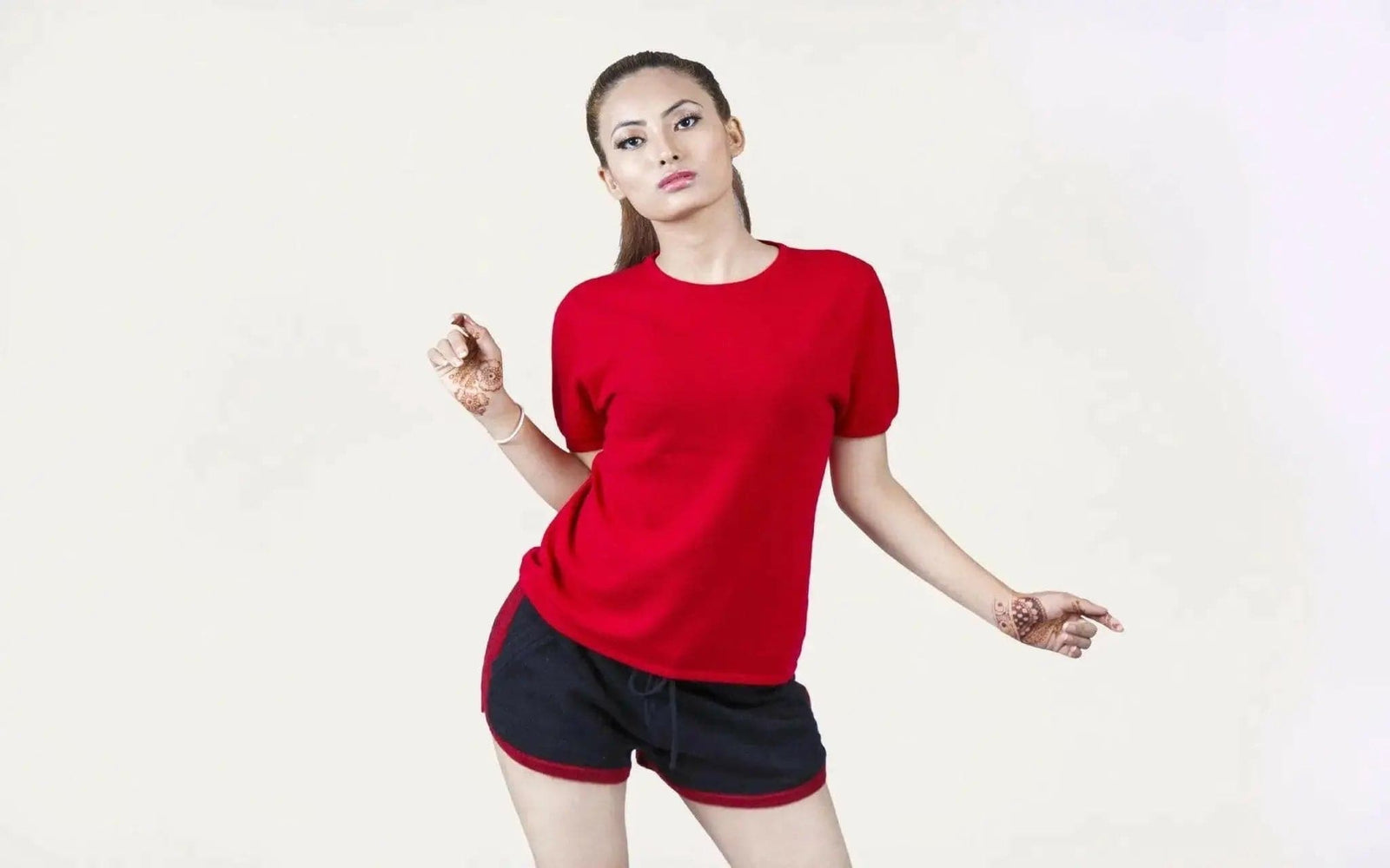Woman in red shirt and black shorts modeling Italian Cashmere Turtle Neck T-Shirt with flattering turtle neck design