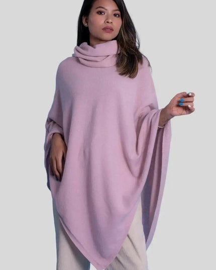 Woman in pink cashmere turtle neck poncho against white background