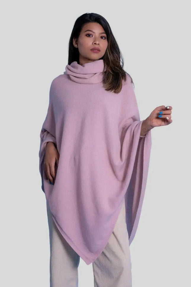 Woman in pink cashmere turtle neck poncho against white background