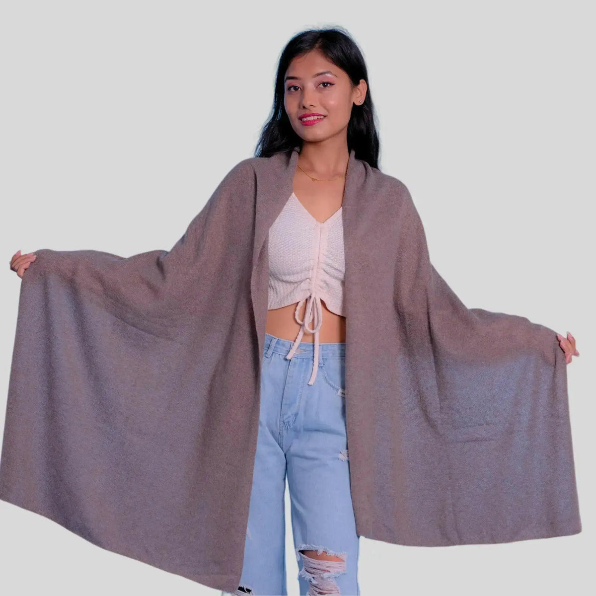 Woman in grey cape, white top, and blue jeans wearing Luxurious Italian Cashmere Scarf for winter wardrobe