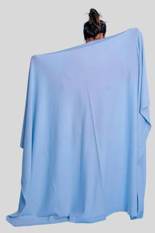 Woman wearing blue poncho with luxurious Italian cashmere throw blanket